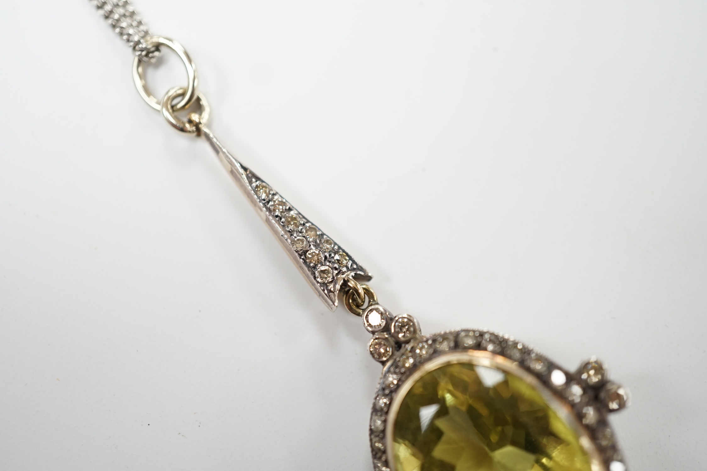 A late Victorian yellow metal and single stone oval cut citrine set drop pendant, with diamond set border and bale, 53mm, on a later 375 white metal chain, 50cm, gross weight 11.2 grams. Good condition.